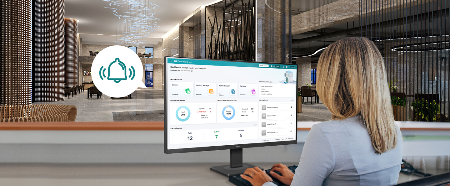 The image shows a hotel staff member monitoring the dashboard screen provided by LG Pro:Centric Cloud.